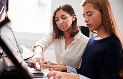piano teacher and student
                sitting at a piano